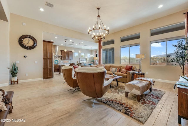 living area with baseboards, light wood finished floors, visible vents, and a notable chandelier