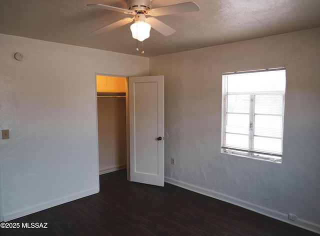 unfurnished bedroom featuring a ceiling fan, a closet, baseboards, and dark wood-type flooring