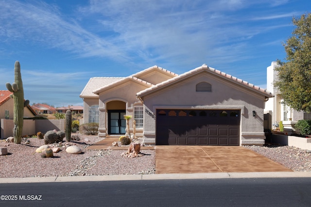 mediterranean / spanish house featuring a garage, driveway, a tile roof, and stucco siding