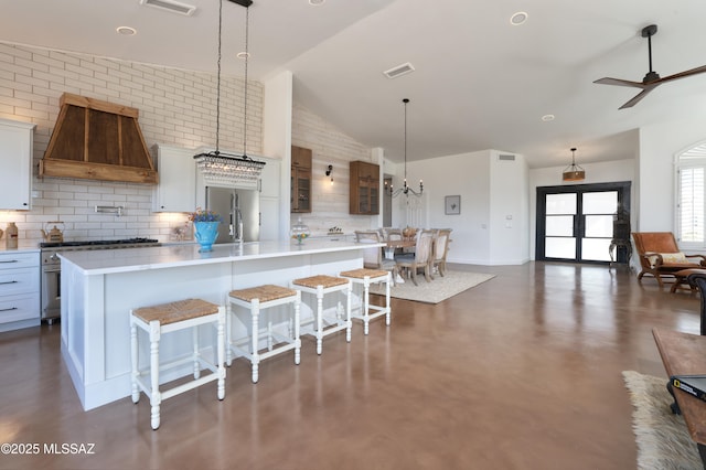 kitchen with a breakfast bar, a spacious island, light countertops, hanging light fixtures, and custom range hood