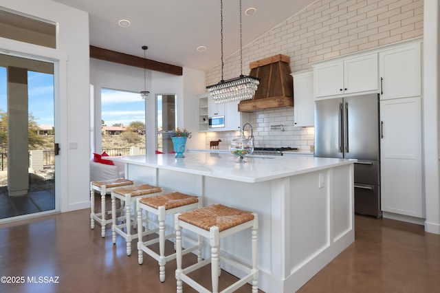 kitchen with white cabinets, appliances with stainless steel finishes, a breakfast bar, custom exhaust hood, and pendant lighting