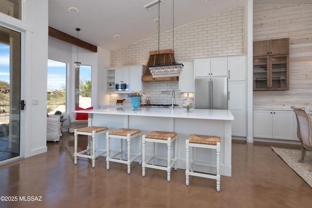 kitchen with white cabinets, a kitchen breakfast bar, decorative light fixtures, built in appliances, and light countertops