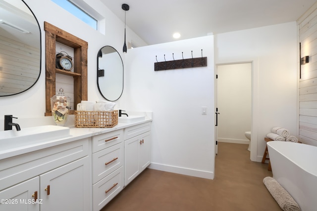 bathroom with double vanity, a freestanding tub, a sink, and toilet