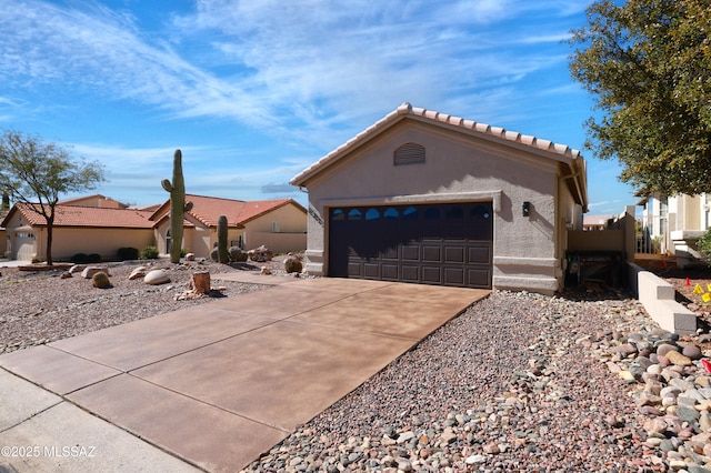 mediterranean / spanish house with driveway, a tiled roof, an attached garage, and stucco siding