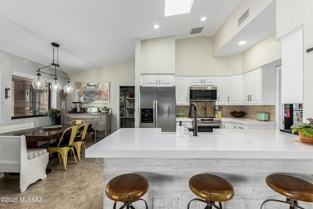 kitchen with white cabinetry, vaulted ceiling with skylight, visible vents, and stainless steel appliances
