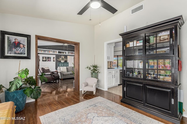living area with ceiling fan, visible vents, baseboards, and wood finished floors