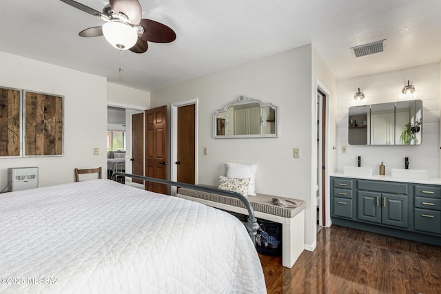 bedroom with visible vents, connected bathroom, dark wood-type flooring, ceiling fan, and a sink
