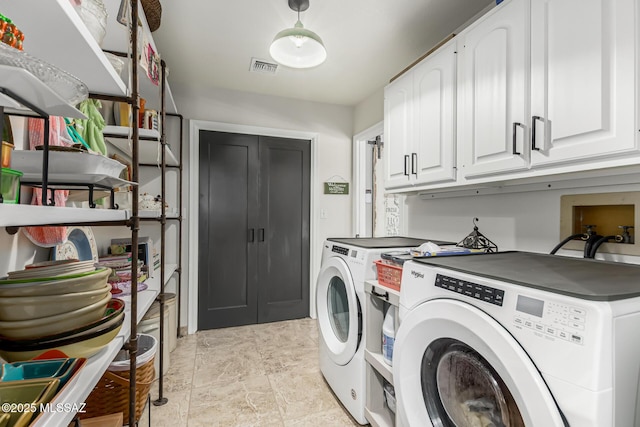 clothes washing area featuring visible vents, cabinet space, and washer and clothes dryer