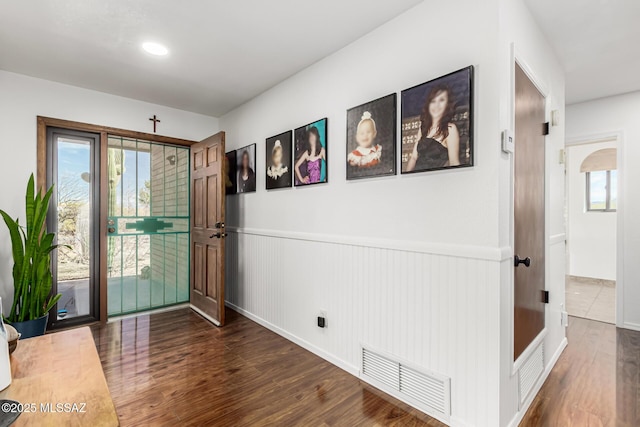 entrance foyer with wood finished floors, visible vents, a wealth of natural light, and wainscoting