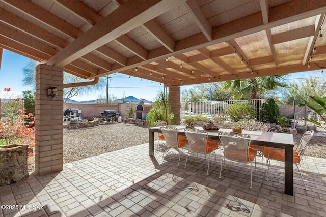 view of patio featuring outdoor dining space, a fenced backyard, and a mountain view
