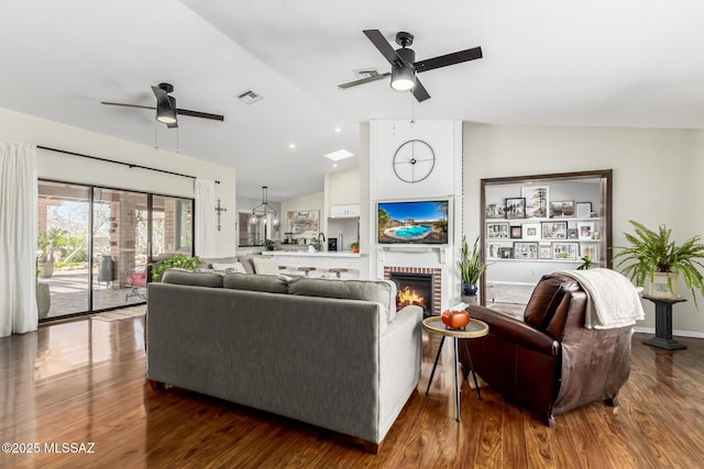 living room featuring visible vents, lofted ceiling, ceiling fan, and wood finished floors