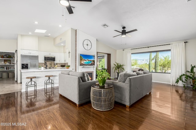 living room with visible vents, ceiling fan, and wood finished floors