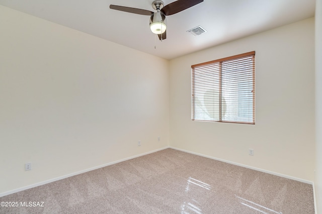 spare room with light carpet, baseboards, visible vents, and a ceiling fan