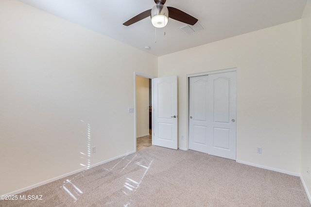 unfurnished bedroom featuring ceiling fan, light colored carpet, visible vents, baseboards, and a closet