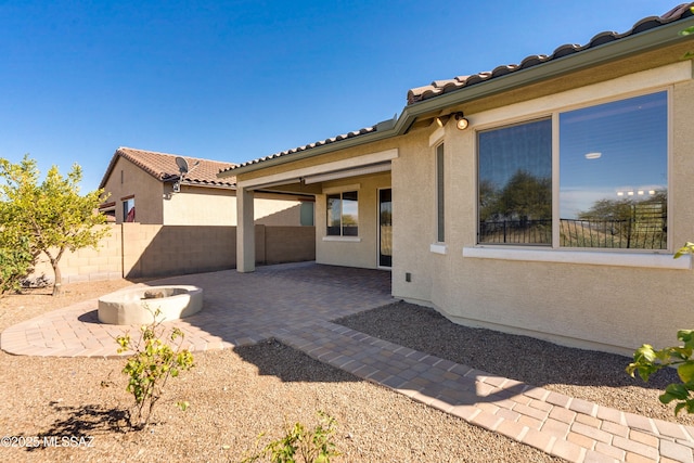 exterior space with a fire pit, a patio, a tile roof, fence, and stucco siding