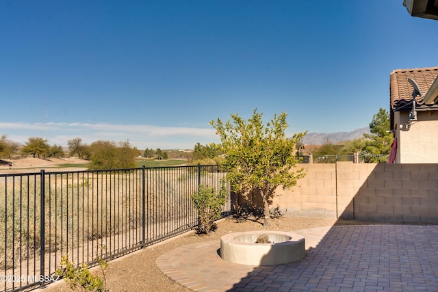 view of patio with an outdoor fire pit, a fenced backyard, and a mountain view