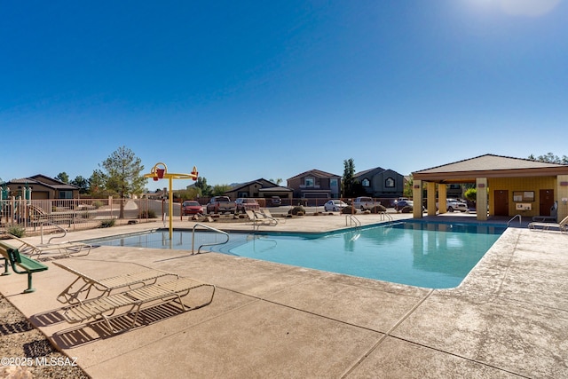 pool with a residential view, a patio area, and fence