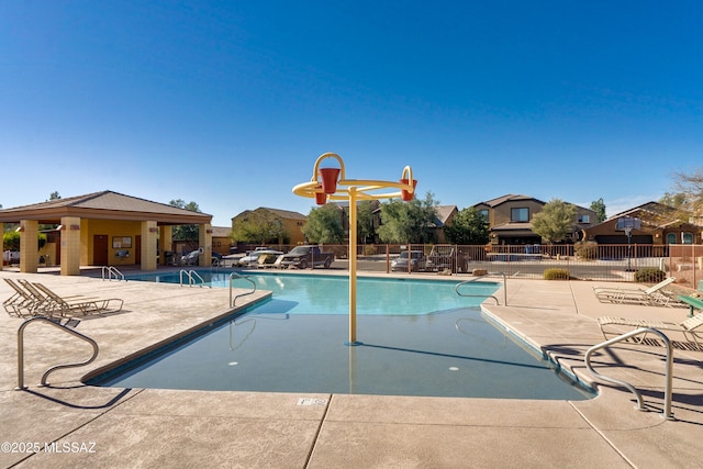 community pool featuring a residential view, fence, and a patio