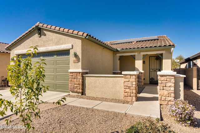 mediterranean / spanish house with stone siding, roof mounted solar panels, an attached garage, and stucco siding