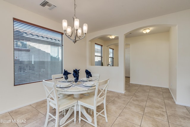 dining space with a chandelier, arched walkways, light tile patterned flooring, visible vents, and baseboards