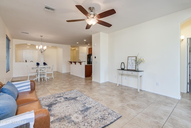 living area with arched walkways, light tile patterned floors, visible vents, baseboards, and ceiling fan with notable chandelier