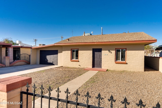 ranch-style house with a garage, concrete driveway, roof with shingles, and fence