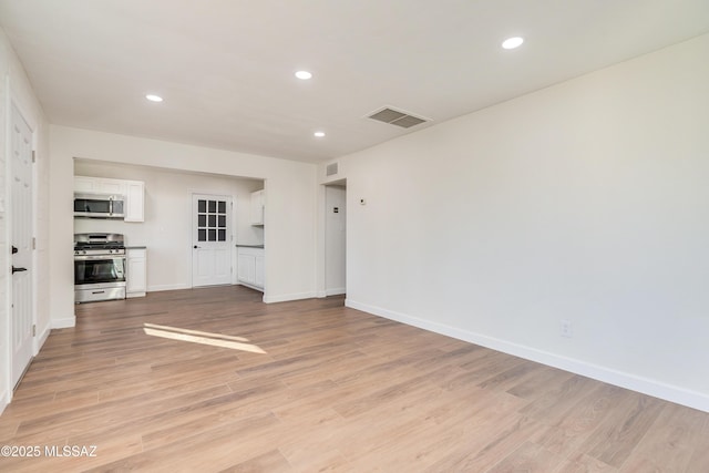 spare room featuring light wood-style floors, recessed lighting, visible vents, and baseboards