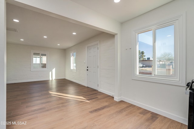 entryway with brick wall, wood finished floors, and baseboards