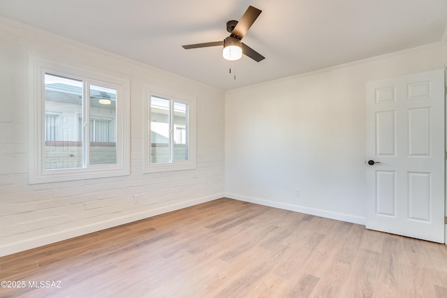 empty room with a ceiling fan, light wood-type flooring, crown molding, and baseboards