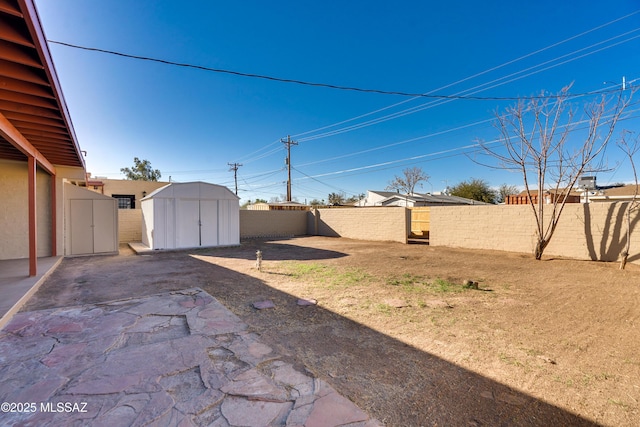 view of yard featuring a shed, a patio, a fenced backyard, and an outdoor structure