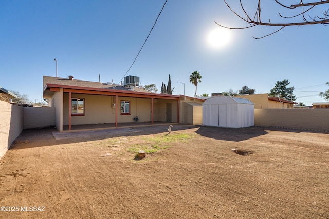 rear view of property featuring a patio, a storage unit, central AC unit, a fenced backyard, and an outdoor structure