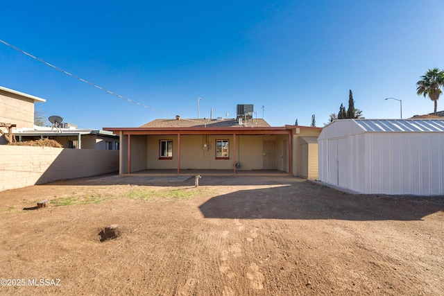 back of property featuring a patio, central air condition unit, an outdoor structure, fence, and a storage unit