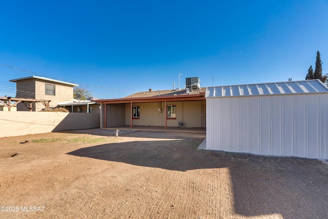 rear view of house featuring central AC unit and fence