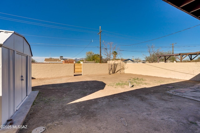 view of yard with a shed, a fenced backyard, and an outbuilding