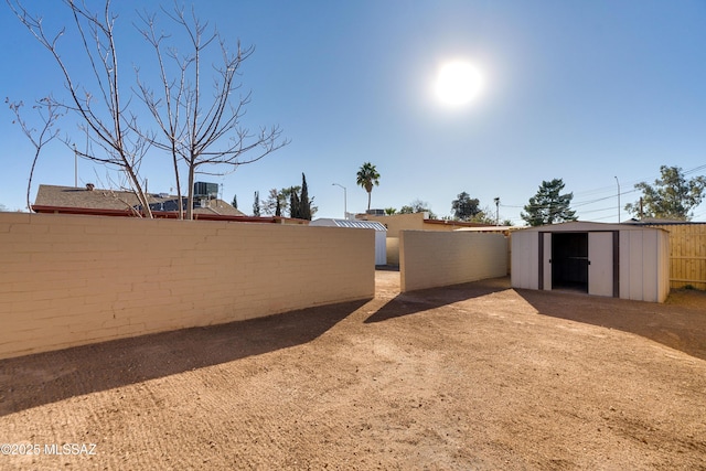 view of yard with an outbuilding, fence, and a storage shed