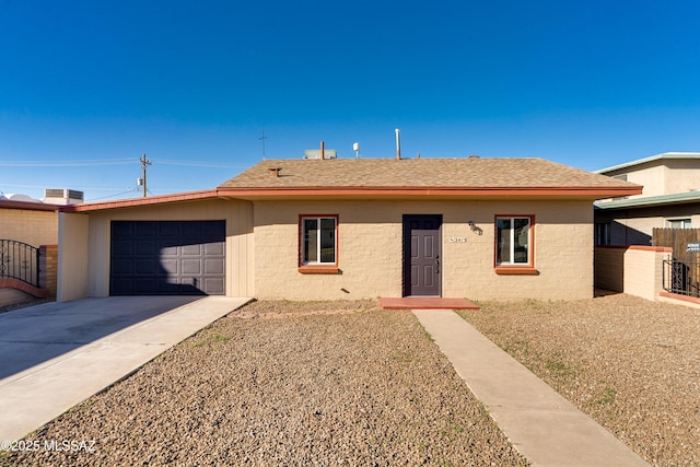 single story home featuring a garage, a shingled roof, fence, and concrete driveway