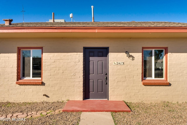 property entrance featuring roof with shingles