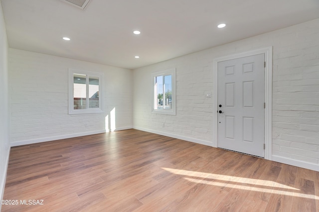 entryway featuring light wood-type flooring, brick wall, baseboards, and recessed lighting