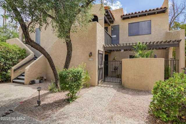 view of front of property with a pergola, fence, a gate, and stucco siding