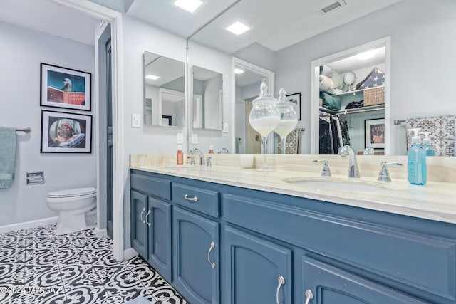 bathroom with toilet, double vanity, visible vents, and a sink