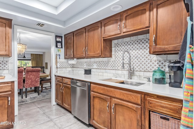 kitchen with brown cabinetry, light countertops, a sink, and stainless steel dishwasher