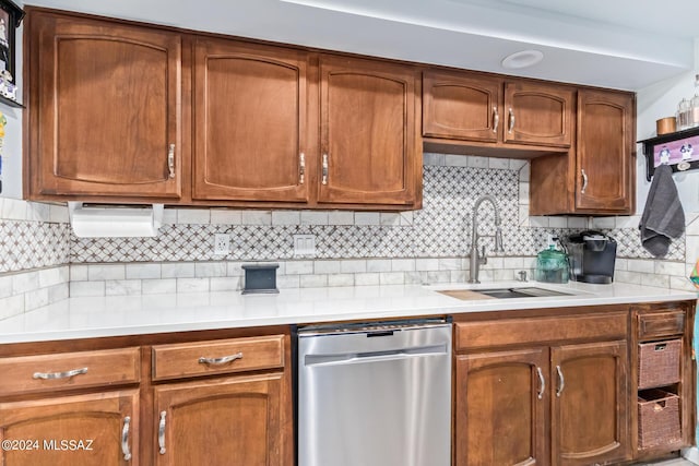 kitchen with a sink, light countertops, stainless steel dishwasher, decorative backsplash, and brown cabinetry