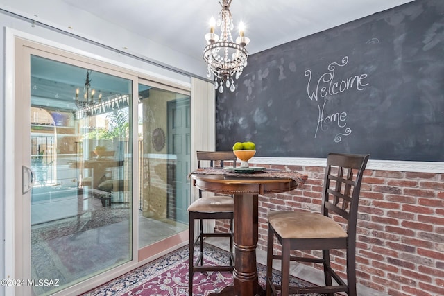 dining room featuring brick wall and a notable chandelier