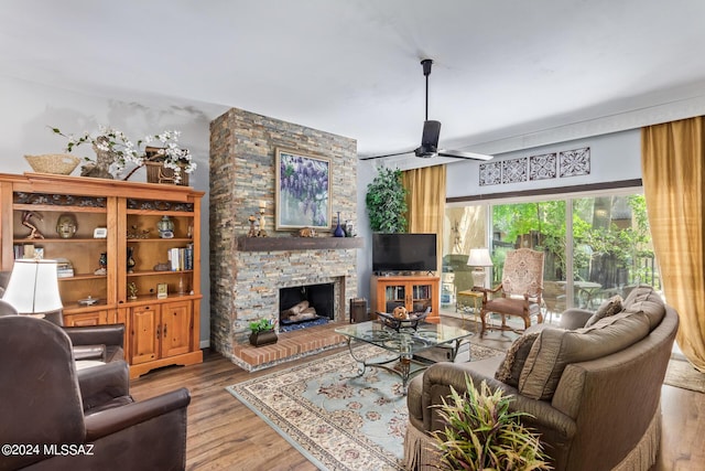 living area featuring a ceiling fan, a fireplace, and light wood-style flooring