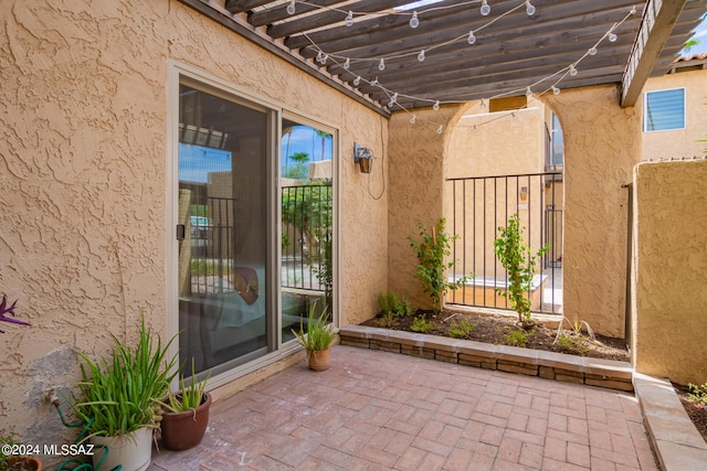 entrance to property featuring a pergola, a patio, and stucco siding