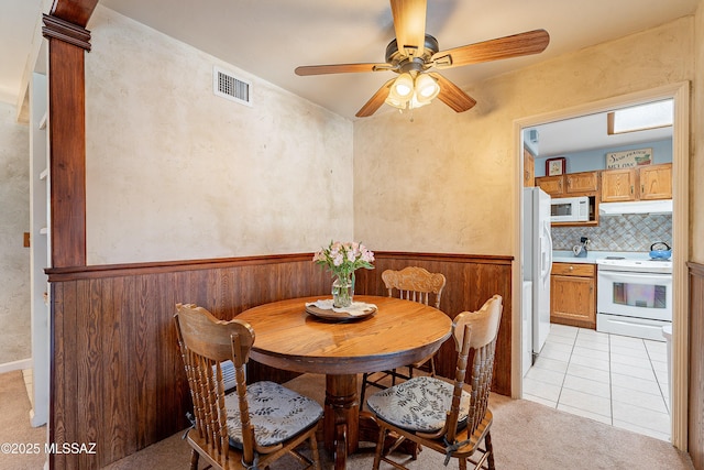 3021 E 2nd St, Tucson, AZ 85716 - dining room featuring a ceiling fan, light carpet, light tile patterned flooring, and wainscoting