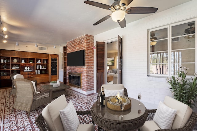 3021 E 2nd St, Tucson, AZ 85716 - living area featuring brick wall, ceiling fan, a brick fireplace, and track lighting