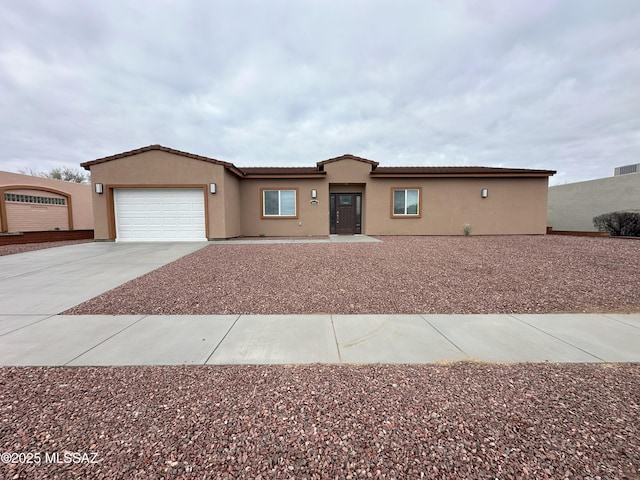 single story home featuring a garage, driveway, a tiled roof, and stucco siding