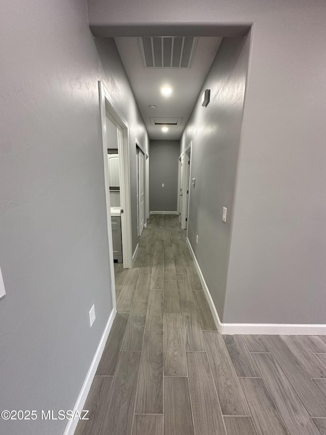 corridor featuring wood finish floors, visible vents, and baseboards