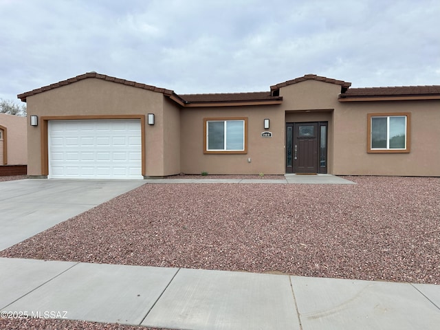 ranch-style house featuring an attached garage, driveway, and stucco siding